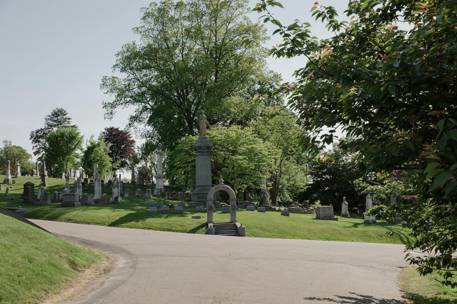 Peaceful scene at Green-Wood Cemetery featuring historic gravestones and lush trees.