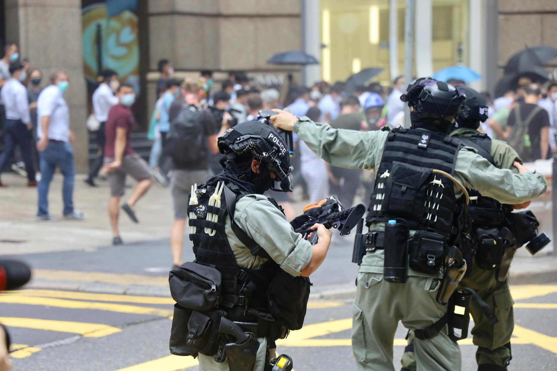 Police officers in protective riot gear during a protest scene outdoors.